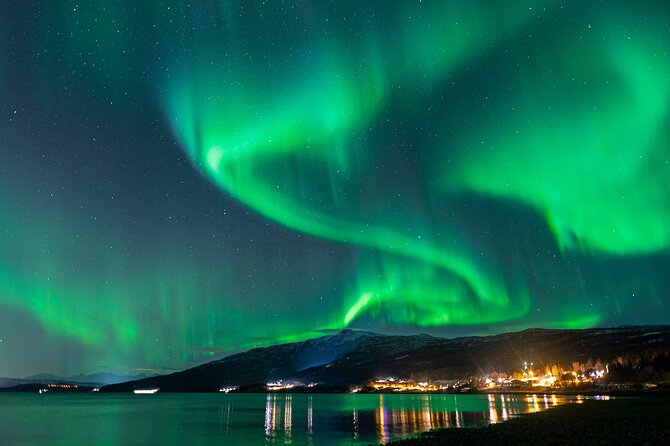 Green aurora over a lit town and lake near Kiruna